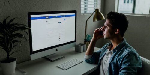 man in blue denim jacket facing turned on monitor